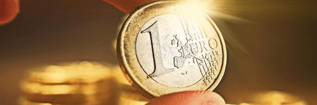 Gros plan sur une pièce de 1 euro tenue entre les doigts avec un effet de lumière.